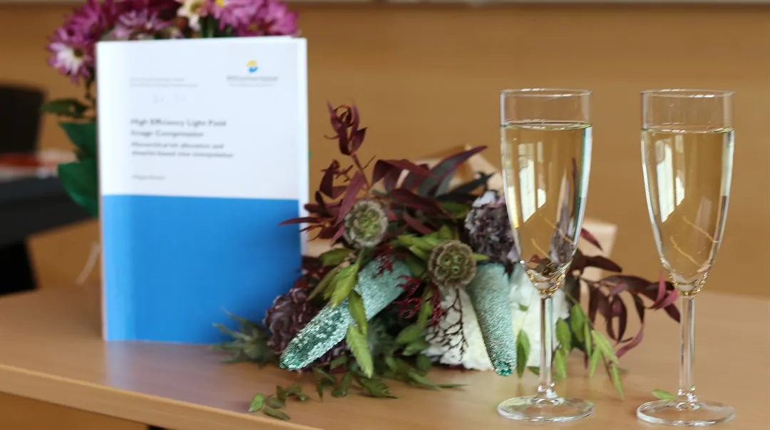 Bild på en avhandling, blommor och två glas med cider