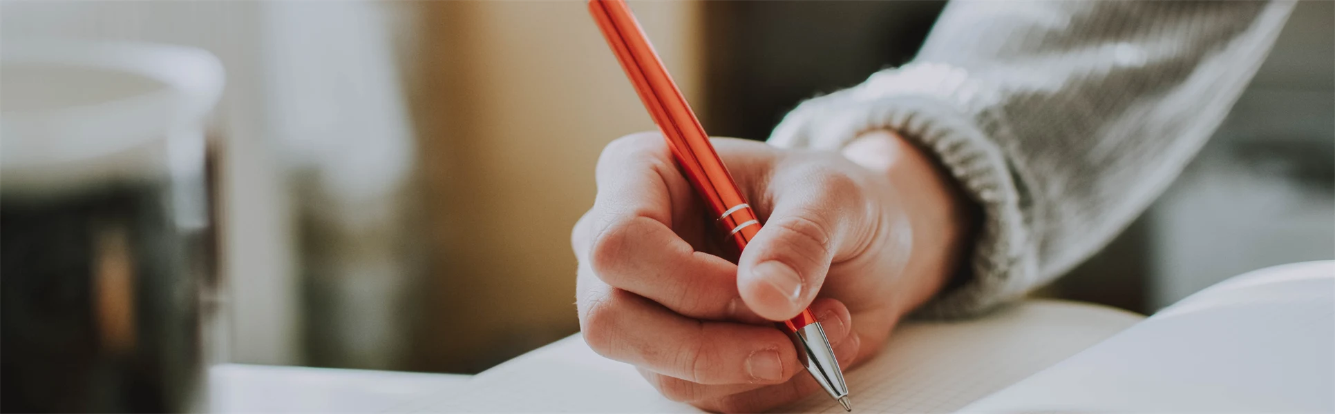  A hand holding a pen and taking notes in a notebook