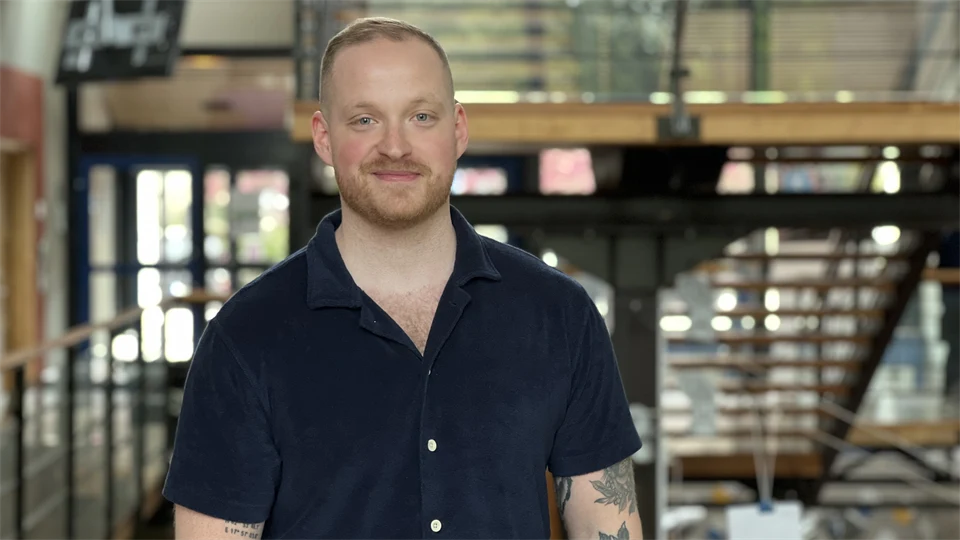En man med mörk tshirt och tatueringar står i ett trapphus