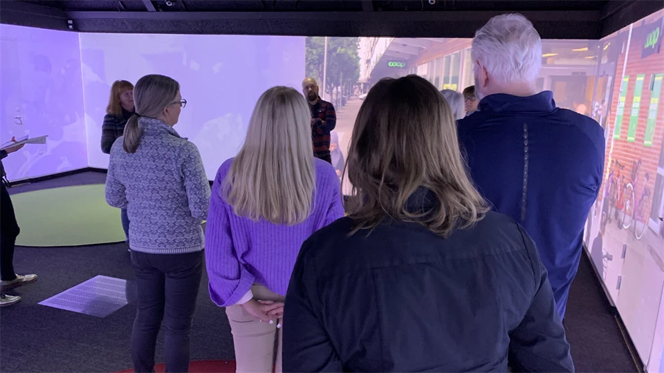 En grupp människor står i ett rum som har projicerade bilder på väggarna.