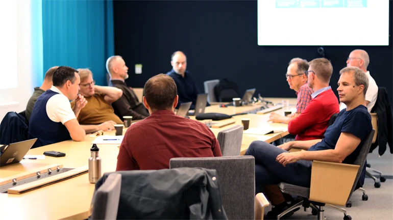 Flera personer sitter runt ett ovalt bord och pratar