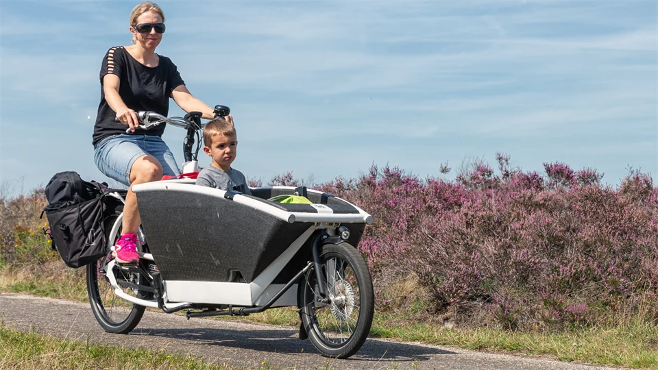 kvinna med barn i sidovagn cyklar i naturen