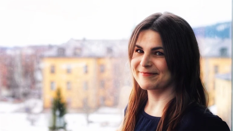 Marie-France tittar in i kameran med campus Östersund i bakgrunden