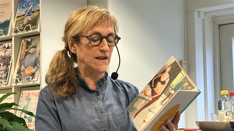 Kvinna läser ur en barnbok i famnen