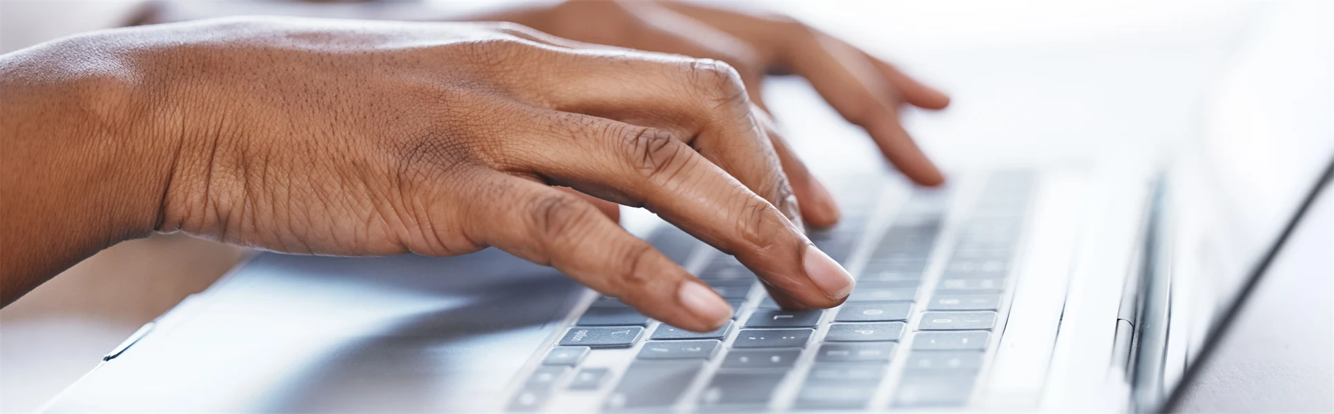 Två händer som skriver på en laptop