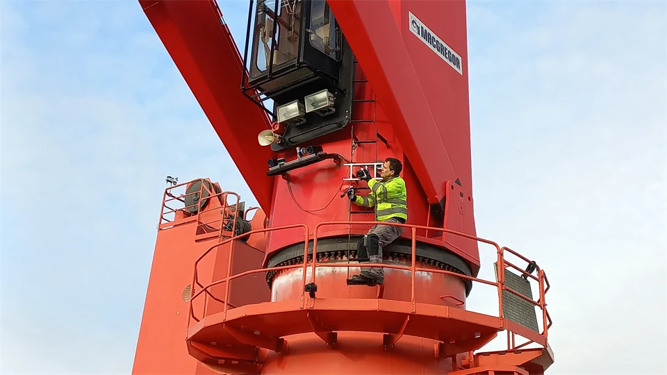 A man is working on a crane at a hangar