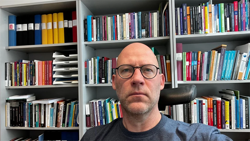 Jimmy Jaldemark framför en bokhylla med böcker