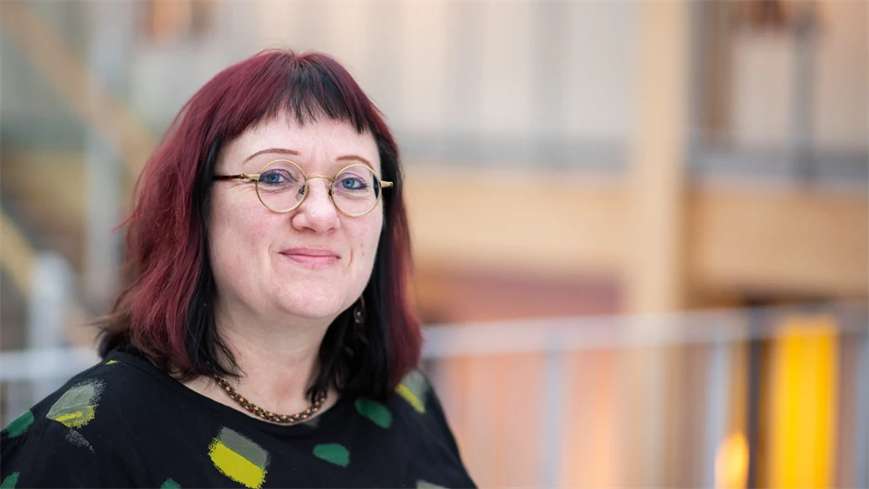 Kvinna med glasögon och rött hår.