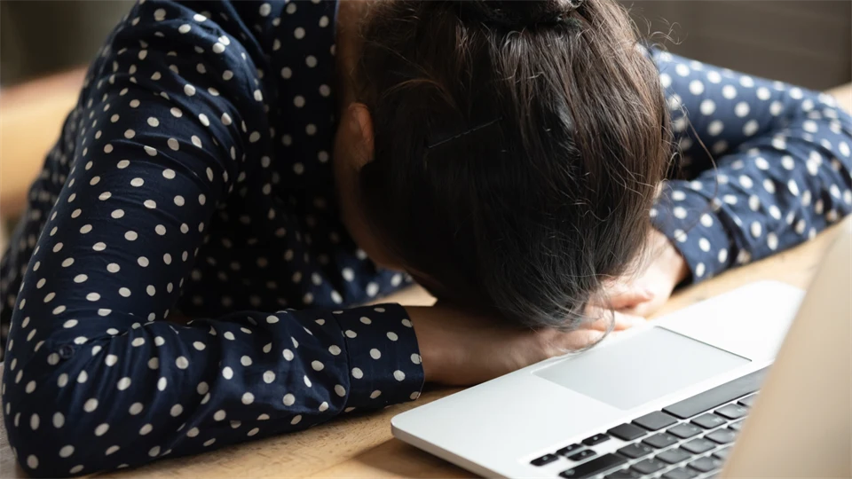 Kvinna vid dator lutar huvudet mot ett bord