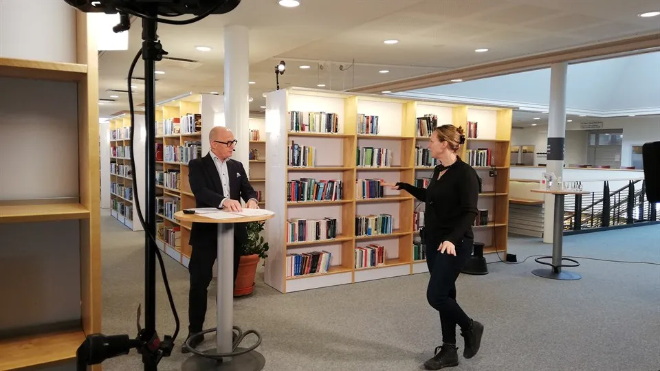 Två personer pratar med varandra. I förgrunden syns inspelningsutrustning.