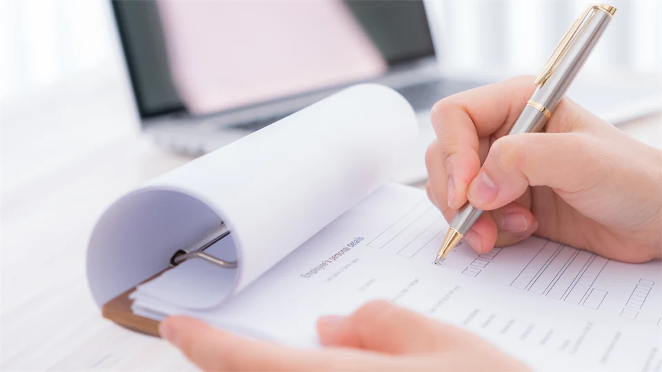 Hand med penna över bedömningsformulär.