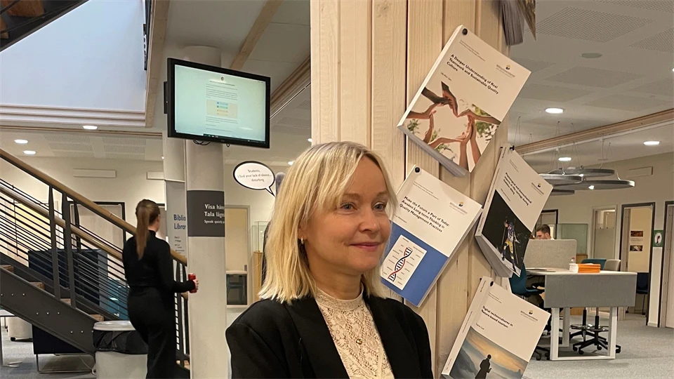 En kvinna i svart kavaj framför sin spikade avhandling