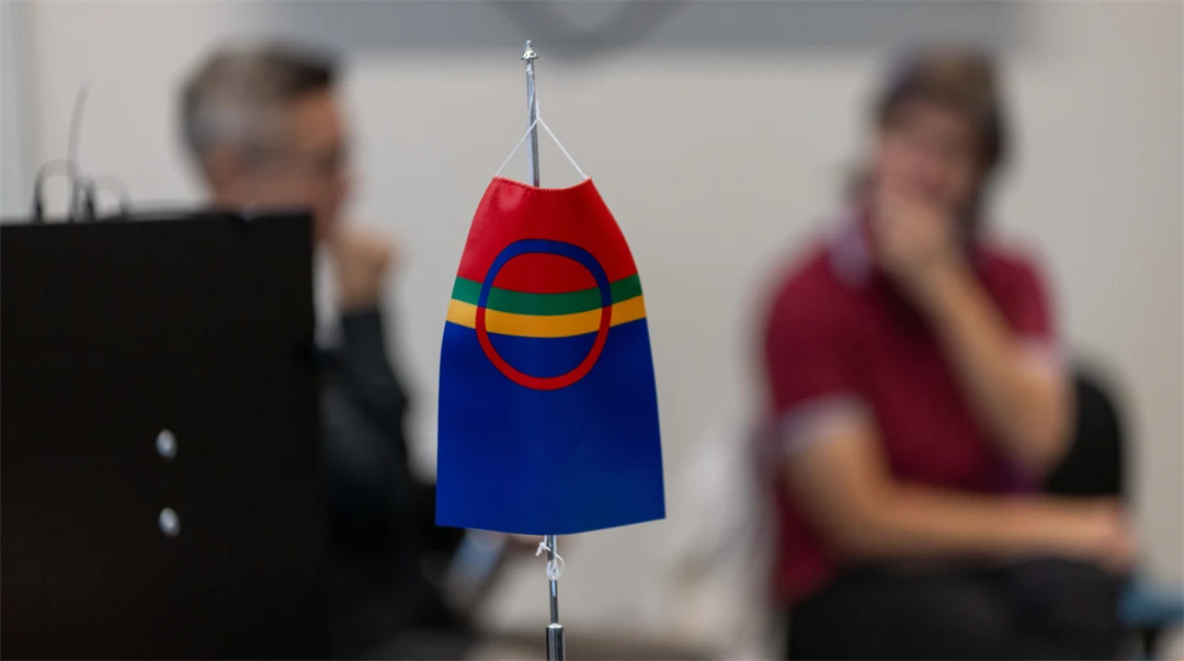Den samiska flaggan i förgrunden och två människor utan fokus i bakgrunden
