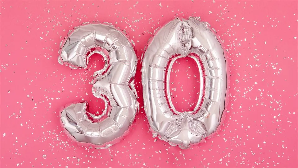 Silverfärgade ballonger i formen 3 och 0 mot en rosa bakgrund med silverglitter på.