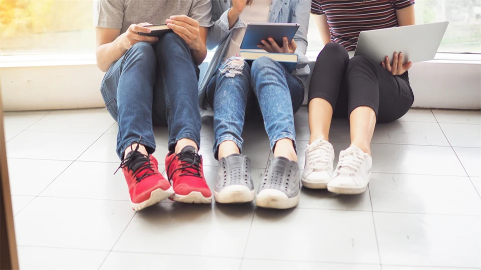 Tre ungdomar i samtal sittandes på golvet, endast benen syns