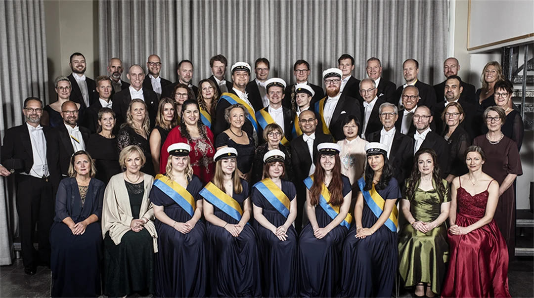 Gruppbild med högtidsklädda personer som sitter och står.