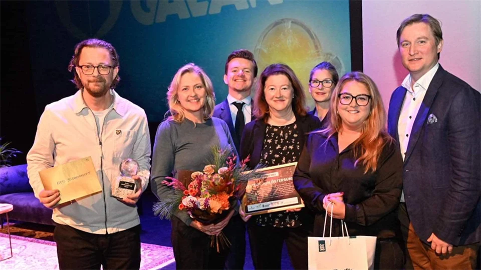 Fyra kvinnor och tre män med priser och blommor