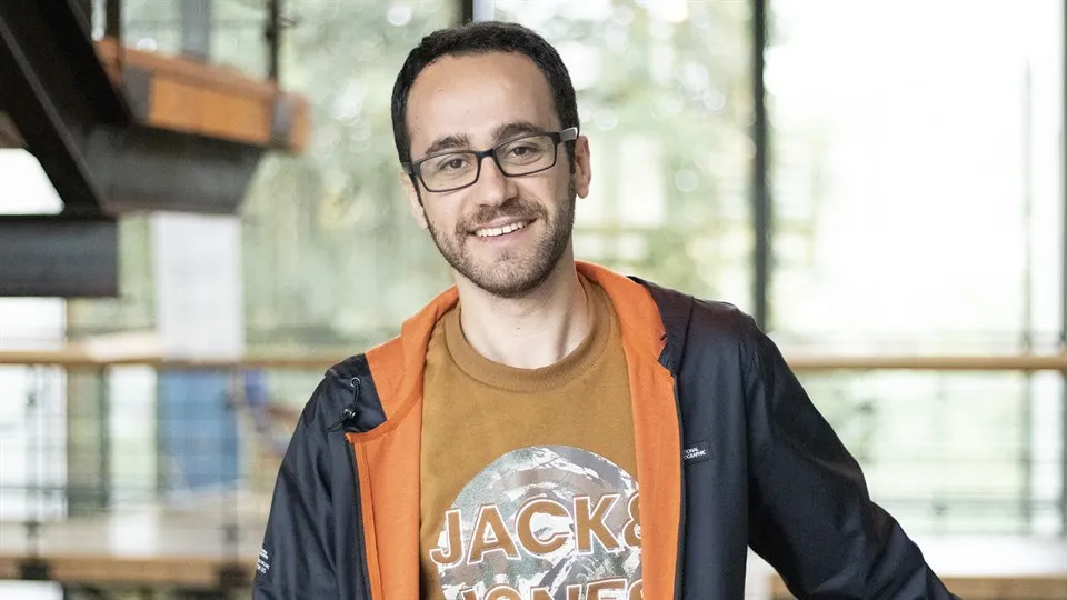 A man in glasses poses in front of the camera.
