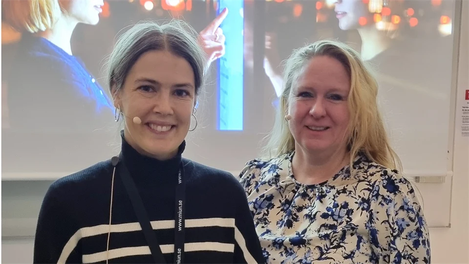 Två kvinnor med headset ler mot kameran.