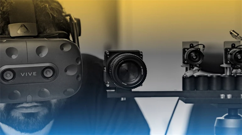 A man with a VR headset on standing next to a set up of smaller cameras.