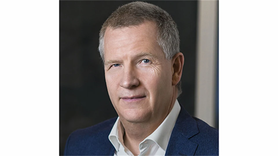 En man i grått hår med vit skjorta och blå kavaj.