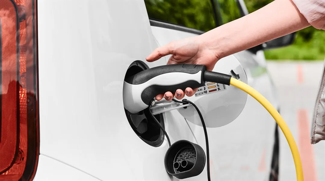 kvinna kopplar ur en laddare från elbil