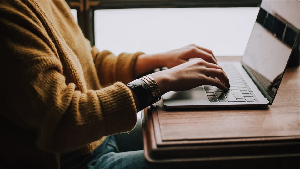 The upper body of a human typing on a computer