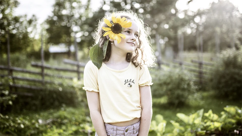 Flicka med solros på äng.