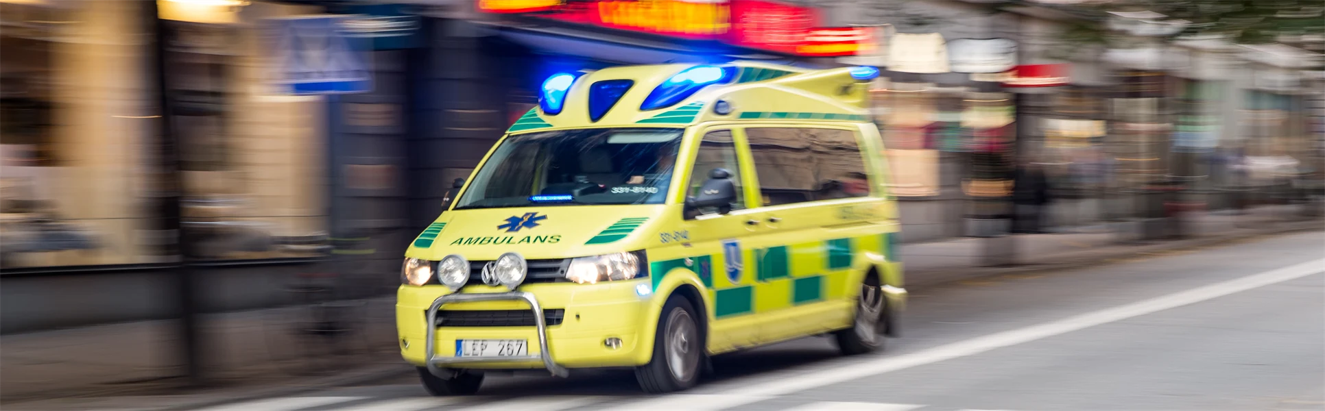 Stor ambulans under utryckning i stadsmiljö.