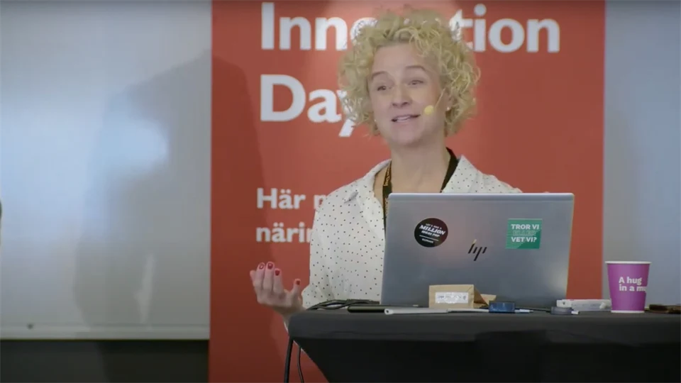 En kvinna föreläser med en laptop framför sig