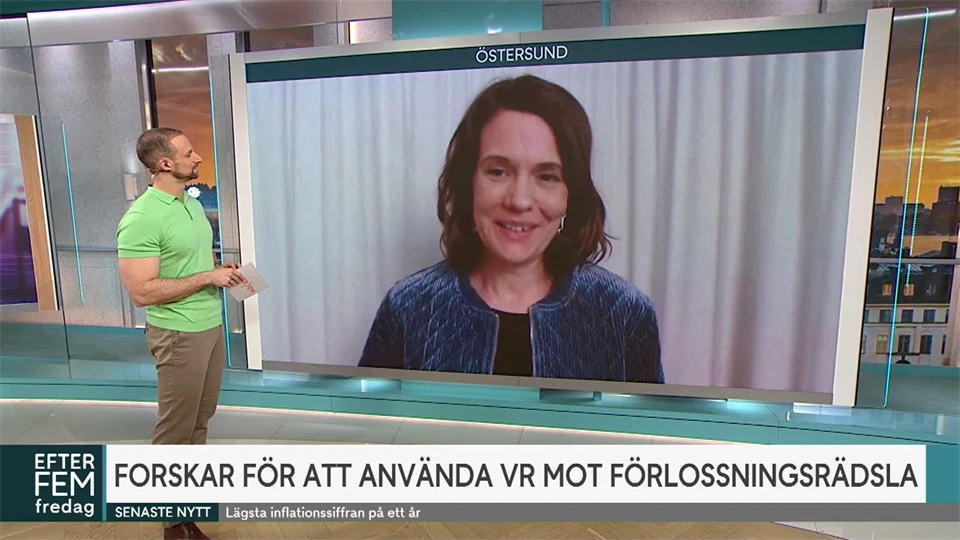 Man står framför en stor bildskärm och intervjuar en kvinna som medverkar via länk