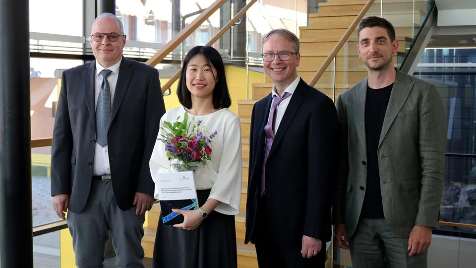 Four persons standing next to eachother smiling toward the camera