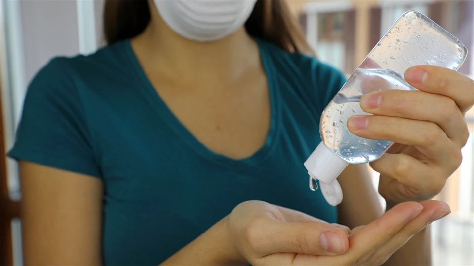 Kvinna med munskydd sprutar alcogel i handen