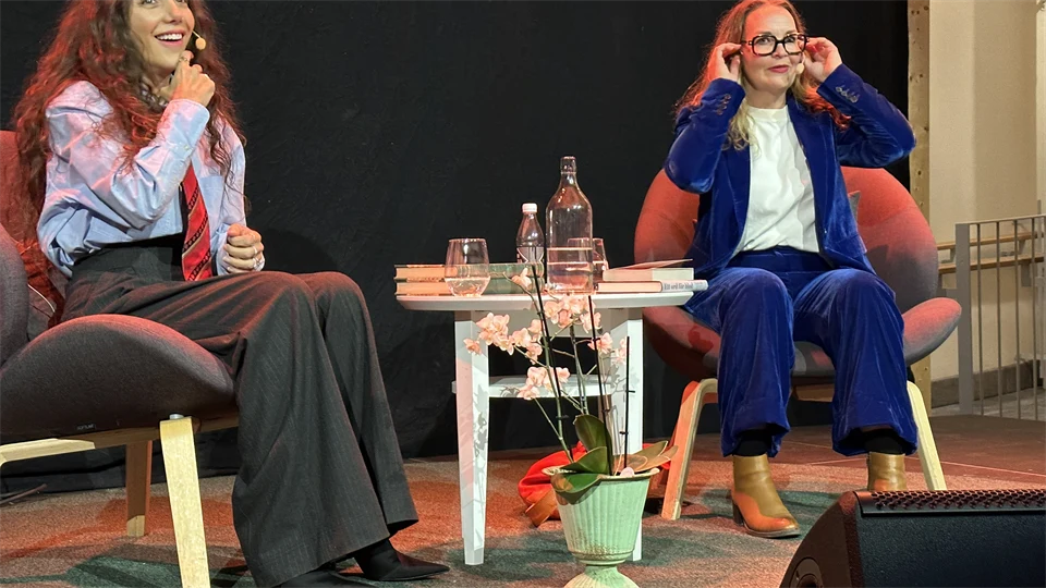 Två kvinnor sitter i varsin stol och ler