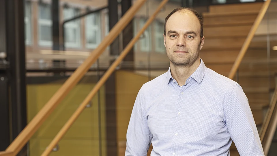 En man med ljusblå skjorta och kort hår poserar framför kameran.