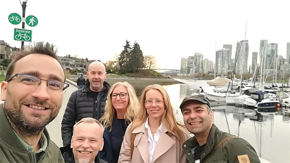 Six people in the foreground with nature, boats and high-rise buildings in the background