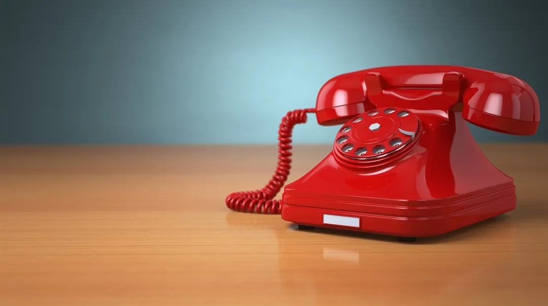 Röd gammal telefon på ett skrivbord.