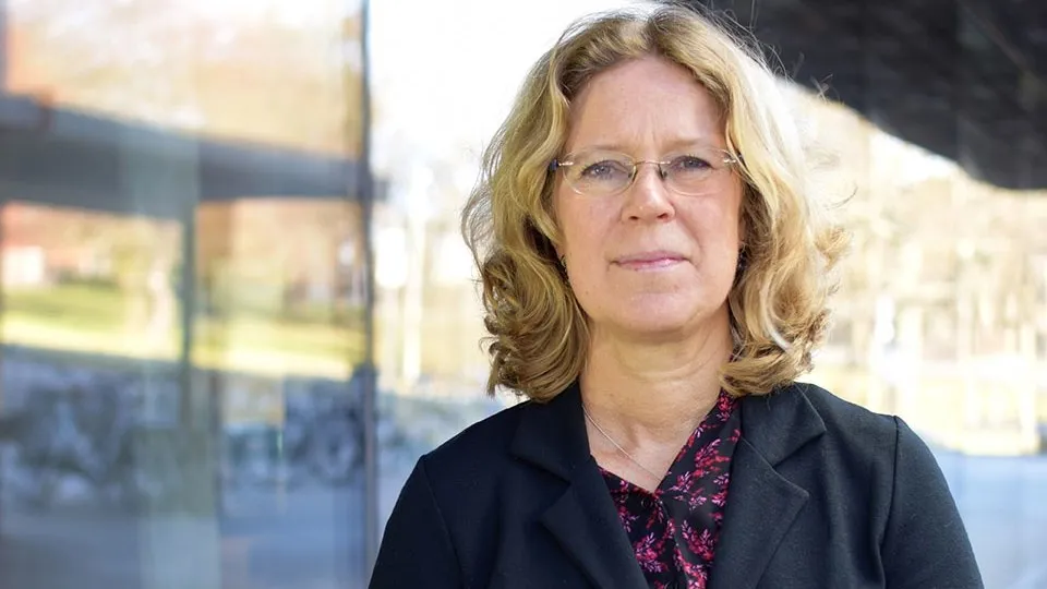 Kvinna med blont hår tittar in i kamera