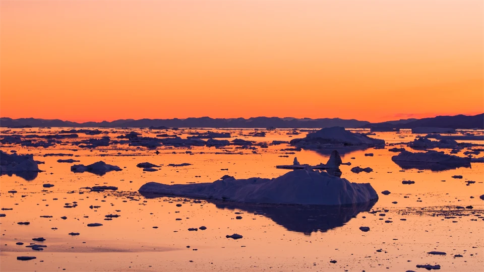 Smältande isar i en orange solnedgång