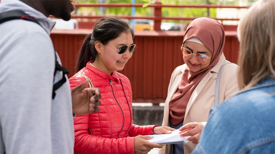 En grupp studenter som står och pratar med varandra utanför campus. 