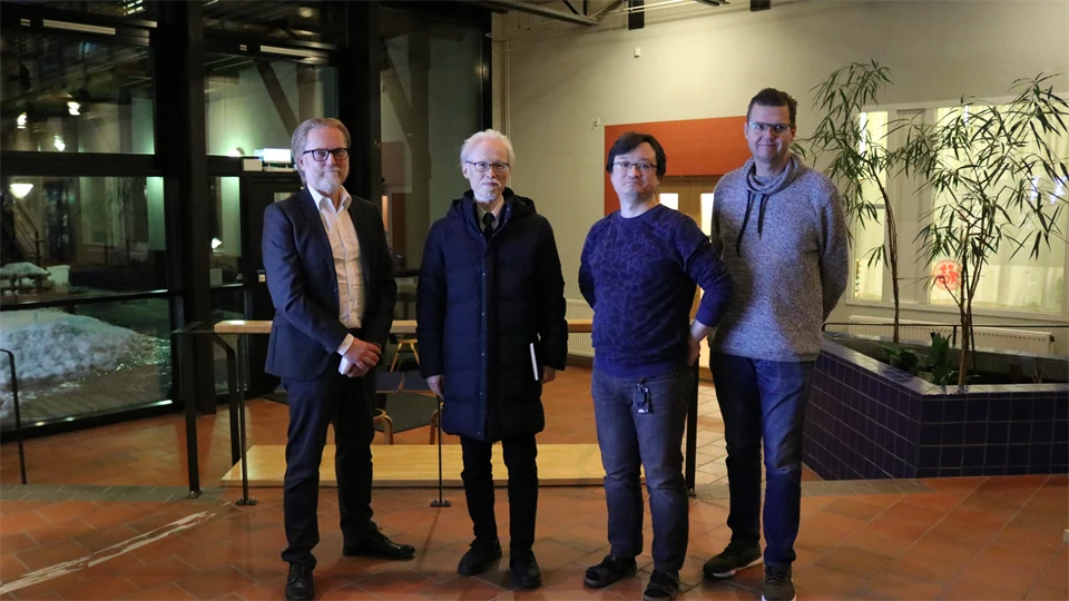 Four men stand in a row.