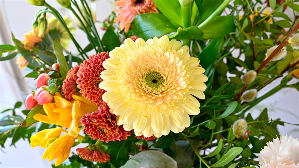 En blombukett med olika blommor i färgerna gul, grön och rosa