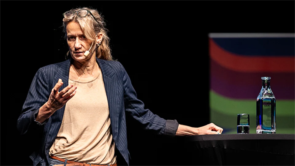 En kvinna i beige tröja som står på en scen