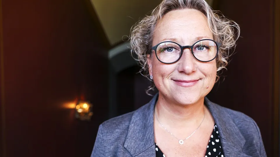Woman with light curly hair and glasses.