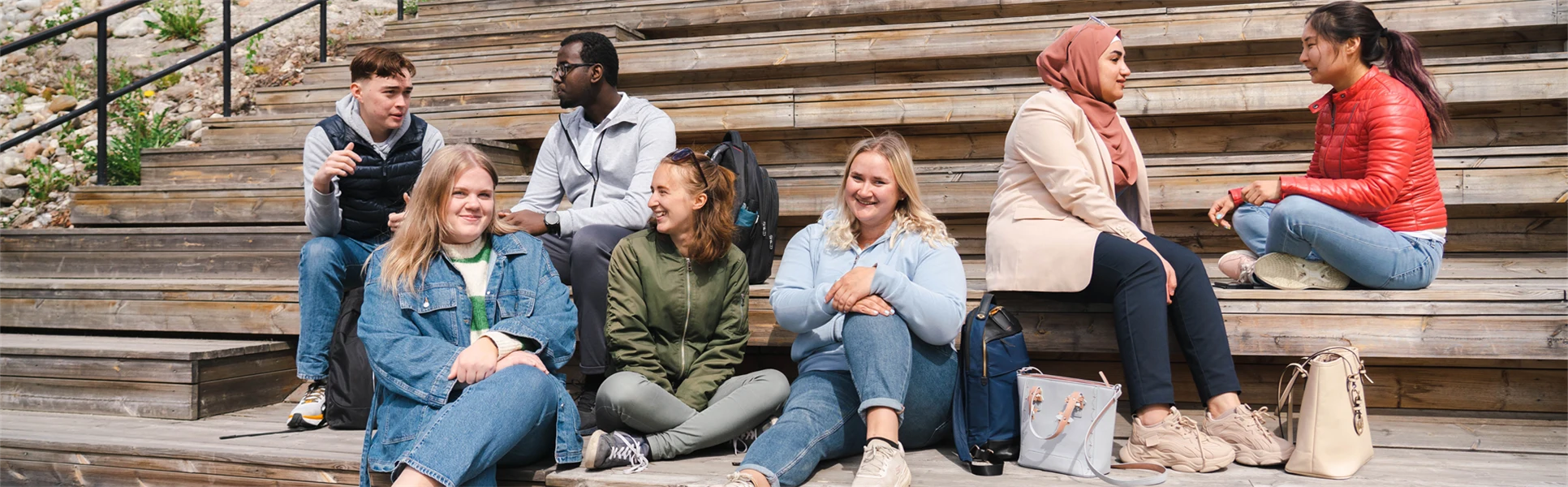 Seven students sitting on a staircase.
