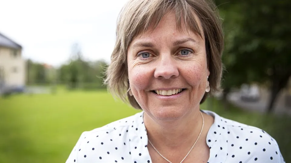 Glad kvinna med vit skjorta med svarta prickar i utomhusmiljö