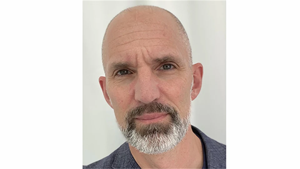 En skallig man med allvarliga ögon och grånande skägg.