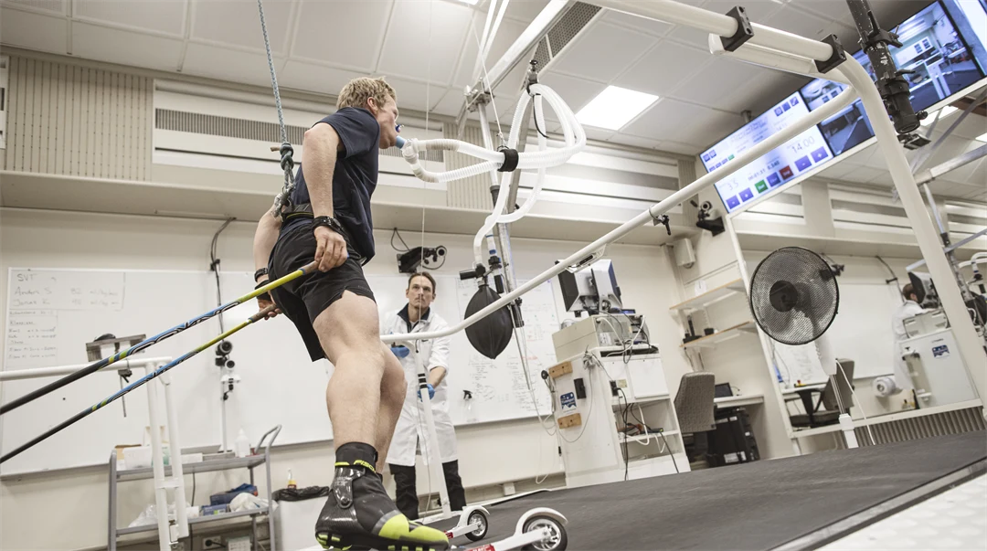 Rullskidåkare med med slangar från en ansiktsmask åker på rullband övervakad av testledare.