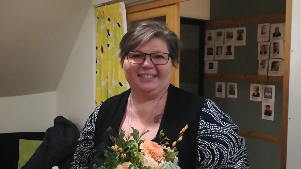 Martina Granholm håller en blombukett i handen. Hon ser in i kameran och ler.