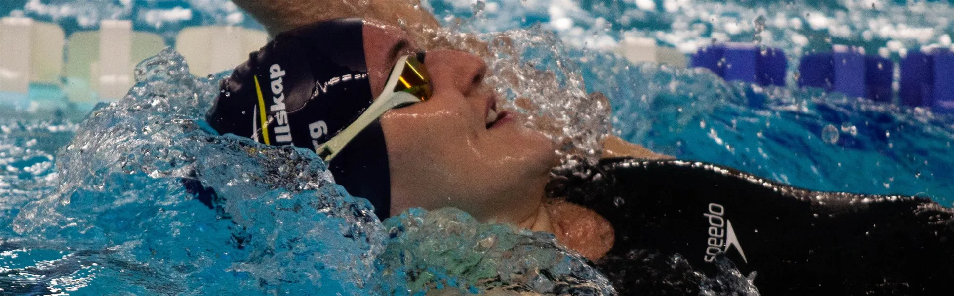 En kvinna som simmar ryggsim.